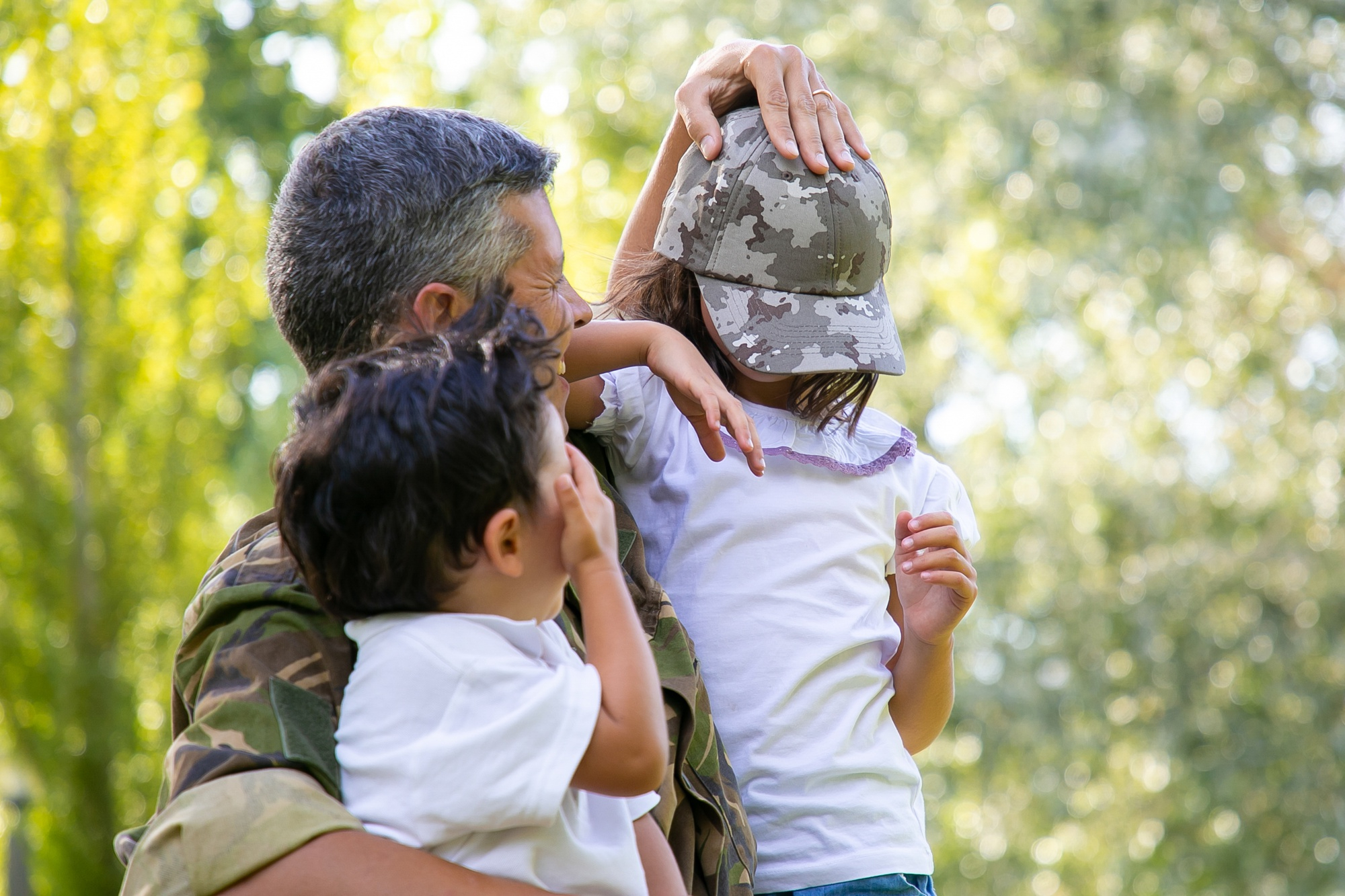 A soldier in uniform reunited with their two young children